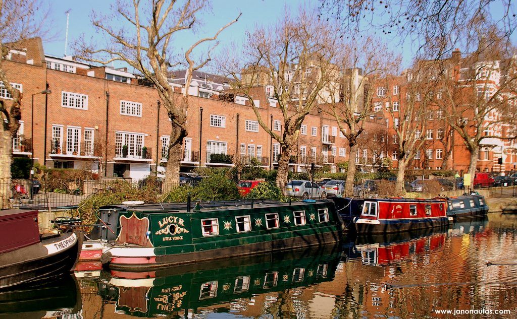 Las casas-barco en el canal Canal de Little Venice en Londres con barcos-casas coloridos y casas al fondo, mostrando un entorno tranquilo y pintoresco.